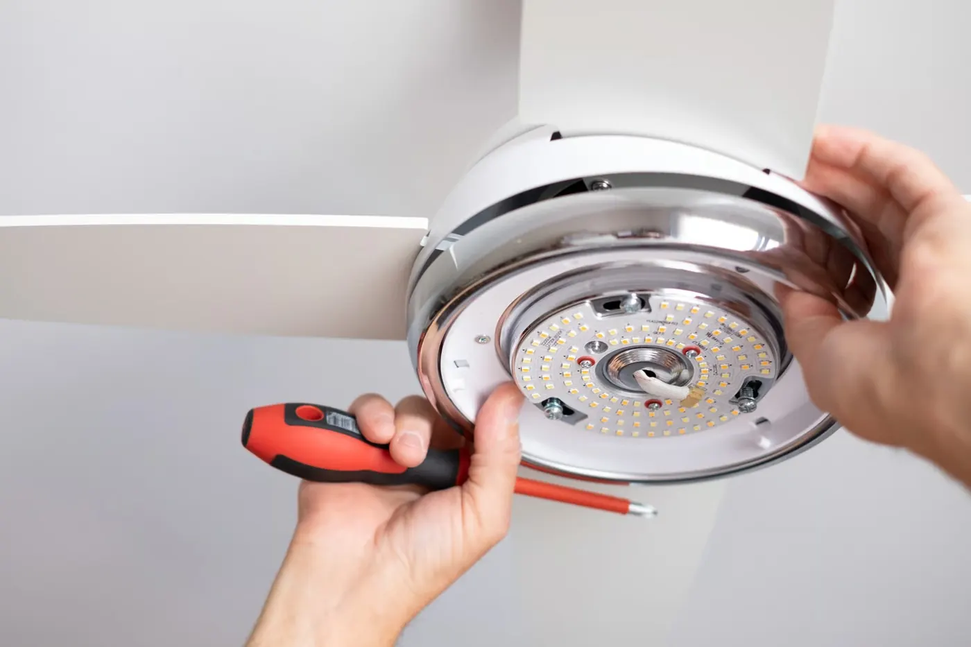 Hands securing the electrical components of a ceiling fan